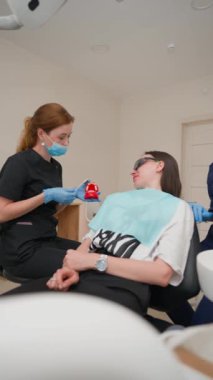Profesyonel Kadın Diş Hekimi, Diş Hekimliği 'nde Diş Fırçalamayı Hastaya Gösteriyor. Güzel kadın doktor. Sağlık ve Tıp Konsepti 'nden. Dikey Video