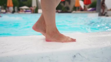 Yakın plan, Güzel Kadın Bacakları Yaz Günü 'nde havuz kenarında yürüyor. Ayak Sağlığı ve Rahatlama konsepti. Tanınmayan kişi. Yavaş Hareket.