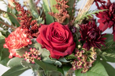 Sonbahar çiçekçisinin kırmızı bir gülün açtığı çiçek buketinin yakın görüntüsü.