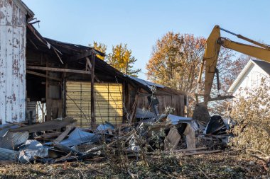Terk edilmiş eski bir ahır binasının yıkımında kullanılan ağır ekipman kazıcısının yakın görüntüsü
