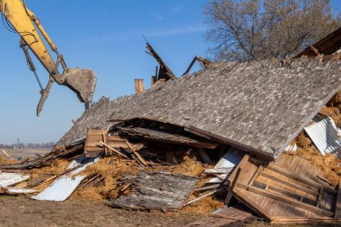 Yıkıma uğrayan eski terk edilmiş bir ahır manzarası. Düşen saman balyaları ve enkaz yığınlarıyla dolu.