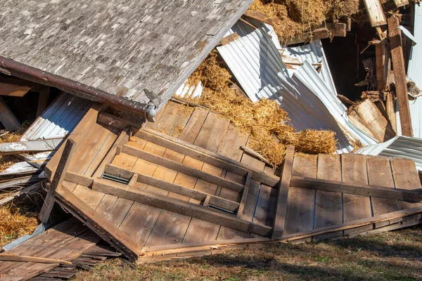 stock image View of an old abandoned barn in the process of demolition, with fallen straw bales and building debris