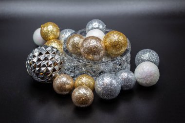 Işıltılı tatil topları ve takılarla dolu, karanlık bir arka planı olan güzel, küçük bir kristal kâsenin soyut görüntüsü.