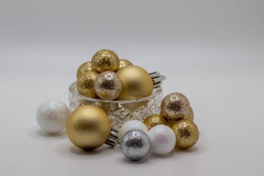 Parıltılı tatil topları ve mücevherlerle dolu, beyaz arka planlı, güzel, küçük, kristal bir kâsenin soyut görüntüsü.