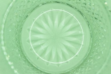 This image shows a macro abstract texture background of a round translucent lead crystal glass surface with a starburst design and diamond cuts, in the color of mint green.