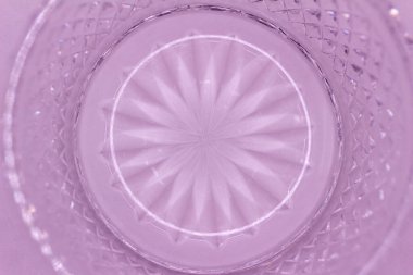 This image shows a macro abstract texture background of a round translucent lead crystal glass surface with a starburst design and diamond cuts, in the color of lavender.