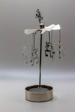 This image shows a macro abstract view of a small metal candle mobile ornament with suspended musical note figures.