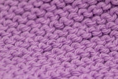Macro defocused abstract texture background of a hand-knitted lavender purple color cloth in a garter stitch pattern