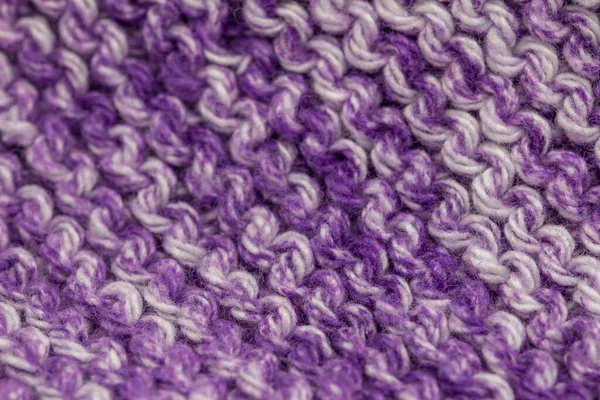 Macro defocused abstract texture background of a hand-knitted purple and white color cloth in a garter stitch pattern
