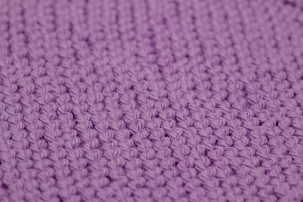 Macro defocused abstract texture background of a hand-knitted lavender purple color cloth in a garter stitch pattern