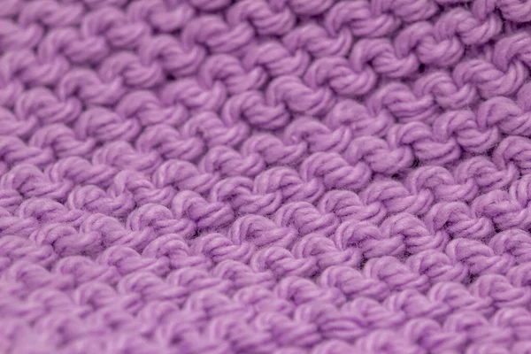 Macro defocused abstract texture background of a hand-knitted lavender purple color cloth in a garter stitch pattern