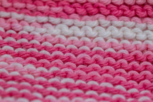 Macro defocused abstract texture background of a hand-knitted pink and white color cloth in a garter stitch pattern