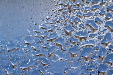 Macro abstract texture background of water droplets and ice forming on an interior glass window pane, with natural designs