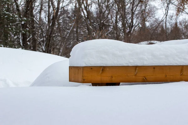 Abstract low level view of a wooden deck and bench, covered with deep heavy snow following a blizzard
