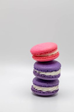 Beyaz bir arka planda, krema dolgulu renkli Fransız Makaron şekerlemelerine yakından bakın.
