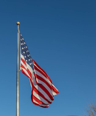 Mavi gökyüzü arka planında bayrak direğinde dalgalanan bir Amerikan bayrağının yakın görüntüsü