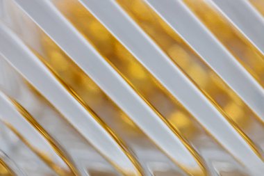 Çapraz çizgileri olan ve altın rengi bokeh ile yansıtan güzel bir kristal cam yüzeyin makro görünümlü soyut desen arkaplanı.