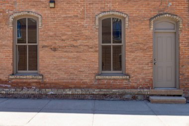 Güneşli bir günde şehrin caddesinde kemerli camları olan, 19. yüzyıldan kalma hoş bir tuğla bina önü.