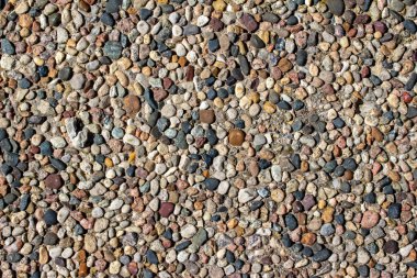 Parlak güneş ışığı altında taşları ve çakılları olan eski bir toplu yürüyüş yüzeyinin soyut makro dokusu