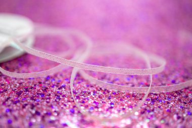 Işıldayan bokeh ve canlı renk ile parlak pembe parıltılı arkaplan üzerine odaklanmış beyaz kumaş kurdele