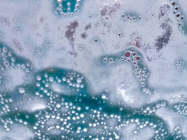 Suyun soyut dokusu ve köpükler otomatik bir oto yıkamada arabanın ön camına püskürtülüyor.