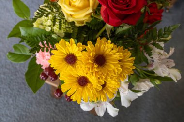 Açık sarı kasımpatıların yer aldığı kapalı bir çiçekçi düzeninde çiçek açan makro çerçeve.