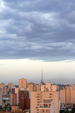 Şehir binalarının üzerinde bulutlu gün batımı