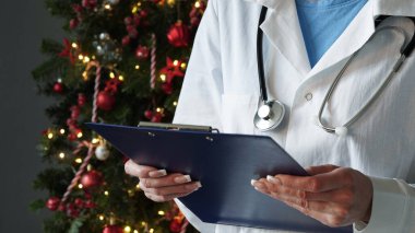Noel ve Yeni Yıl için tıbbi afiş. Beyaz önlüklü bayan bir doktor, steteskop, ellerinde tıbbi kayıtlar için mavi hap tutuyor.