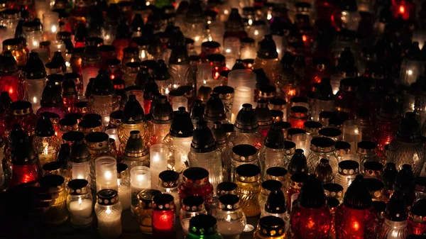 Lot of burning candles at night in cemetery.Glass inextinguishable lamps for cemetery.Day of remembrance and mourning for the dead.All Saints\' Day.Commemorative candles as decor.Cemetery lamps