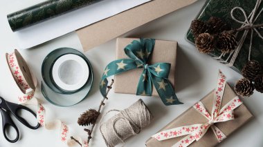 Güzel kurdelelerle bağlanmış hediye kutuları, bovling kağıtları, kurdeleler, halatlar, makas, koniler, kırmızı toplar, beyaz arka plan. Noel için hazırlık, yeni yıl tatili, hediye paketi.