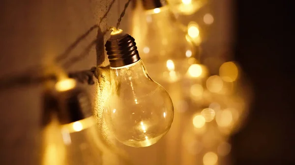 Glowing yellow light bulbs, realistic photo depiction of turning on a tungsten light bulb. Edison lamps in the interior. A garland of light bulbs.Copy space
