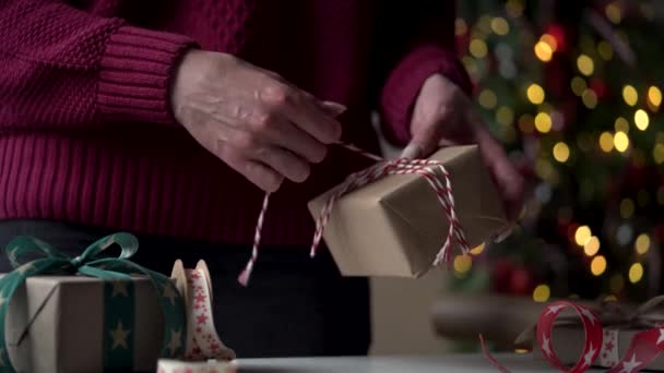 穿着勃艮第毛衣的特写镜头女人们用漂亮的纸和缎带装着许多礼品盒 背景是一棵圣诞树 准备圣诞节 新年假期 礼品包装 — 图库视频影像