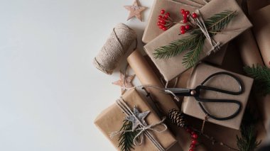 Sıfır israf ve çevre dostu noel konsepti. Kahverengi kağıt, ip ve doğal bitki dekoruna sarılı aile ve arkadaşlar için Noel ve yeni yıl hediyeleri. Kopya alanı, metin için yer. Seçici odak