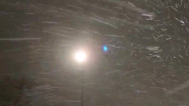  Sokak lambasının ışığına düşen karın dinamik videosu. Mevsimlik kar fırtınası, kar fırtınası. Gece vakti kar yağışı güçlü yağış yağışı, kışın kar taneleri.