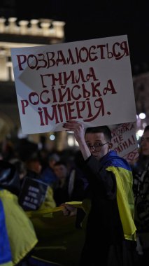 Poland,Krakow,24 February 2023,march Ukrainian refugees anniversary invasion Russian troops territory Ukraine.Year war.Demonstrators with yellow-blue flags Ukraine,anti-war posters in center Krakow.
