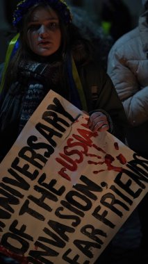 Poland,Krakow,24 February 2023,march Ukrainian refugees anniversary invasion Russian troops territory Ukraine.Year war.Demonstrators with yellow-blue flags Ukraine,anti-war posters in center Krakow.