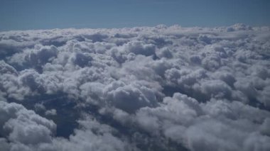  Açık, güneşli bir günde, mavi gökyüzünde, beyaz, pofuduk bulutların üzerindeki bir uçağın penceresinden bakın. Uçakla seyahat, iş uçuşları. Güzel doğa videosu 4K, yavaş çekim.