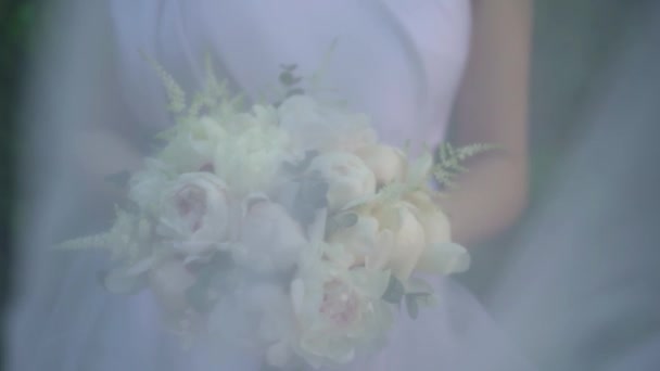 新娘身穿白衣 手里拿着一束美丽精致的白牡丹 黄花菜 绿树旁的桉树 婚礼花 新娘的花束 脆弱的花朵 — 图库视频影像