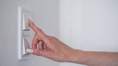 Kapalı çekim yapan kadının eli beyaz duvar lambasını kapatıyor, boşluğu kopyalayıp mesaj yolluyor. Elektrik tasarrufu kavramı. Seçici odak