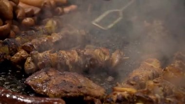 Akşam geleneksel sokak yemekleri festivalinde, kebap, et, sosis ve ızgarada biftek pişirmek. Şehrin ana meydanında şenlik, dumanda lezzetli et pişirmek..