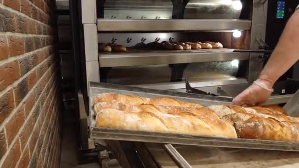 フランスのペストリーを生産するミニベーカリー 焼きたてのホットパンをオーブンから取り出します ベーカリー製品の生産 伝統的なフランスのバゲット — ストック動画