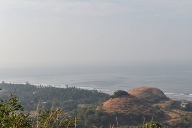 Kıyı, dağ ve ağaçlarla geniş bir alana yayılmış Hint Okyanusu manzarası.