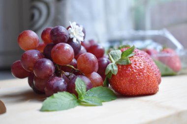 Tahta tepsiye yerleştirilmiş kırmızı üzümler ve çilekler.