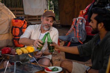Grup turistleri kamp yapar, barbekü yapar, bira içer ve bira şişesini devirir.