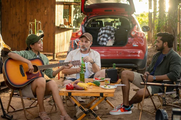 Group tourists drinking beer-alcohol and play guitar together with enjoy and happiness in Summer while camping