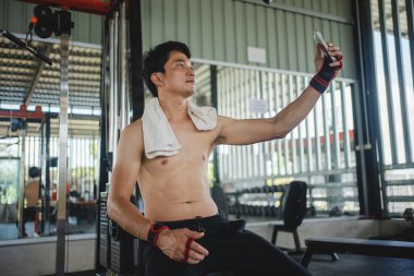 Spor salonundaki egzersizden sonra cep telefonlarını selfie çekmek için kullanan Asyalı erkekler.