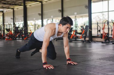 Adam spor salonunda dağa tırmanıyor. Bacaklarını kaldırıp havada hareket eden bir adam. Spor salonu konseptinde sağlık hizmeti.