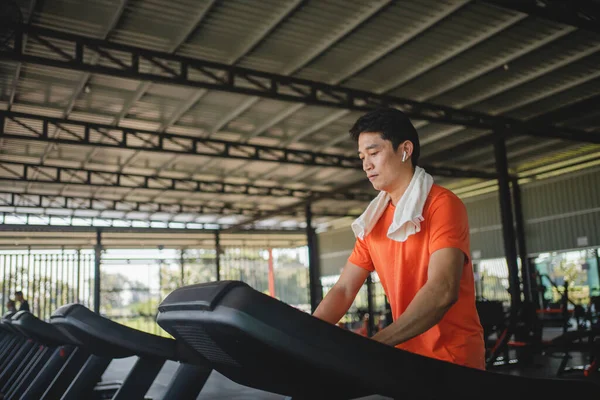 Asian men are happy jogging and running on a treadmill at gym. A man is jogging and doing cardio training. Healthy lifestyle concept. Doing exercise for longer life