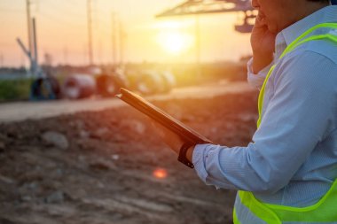 Erkek Mühendis, inşaat alanında çalışmak ve teftiş için cep telefonu kullanıyor ve tablet tutuyor.