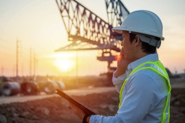 Erkek Mühendis, inşaat alanında çalışmak ve teftiş için cep telefonu kullanıyor ve tablet tutuyor.